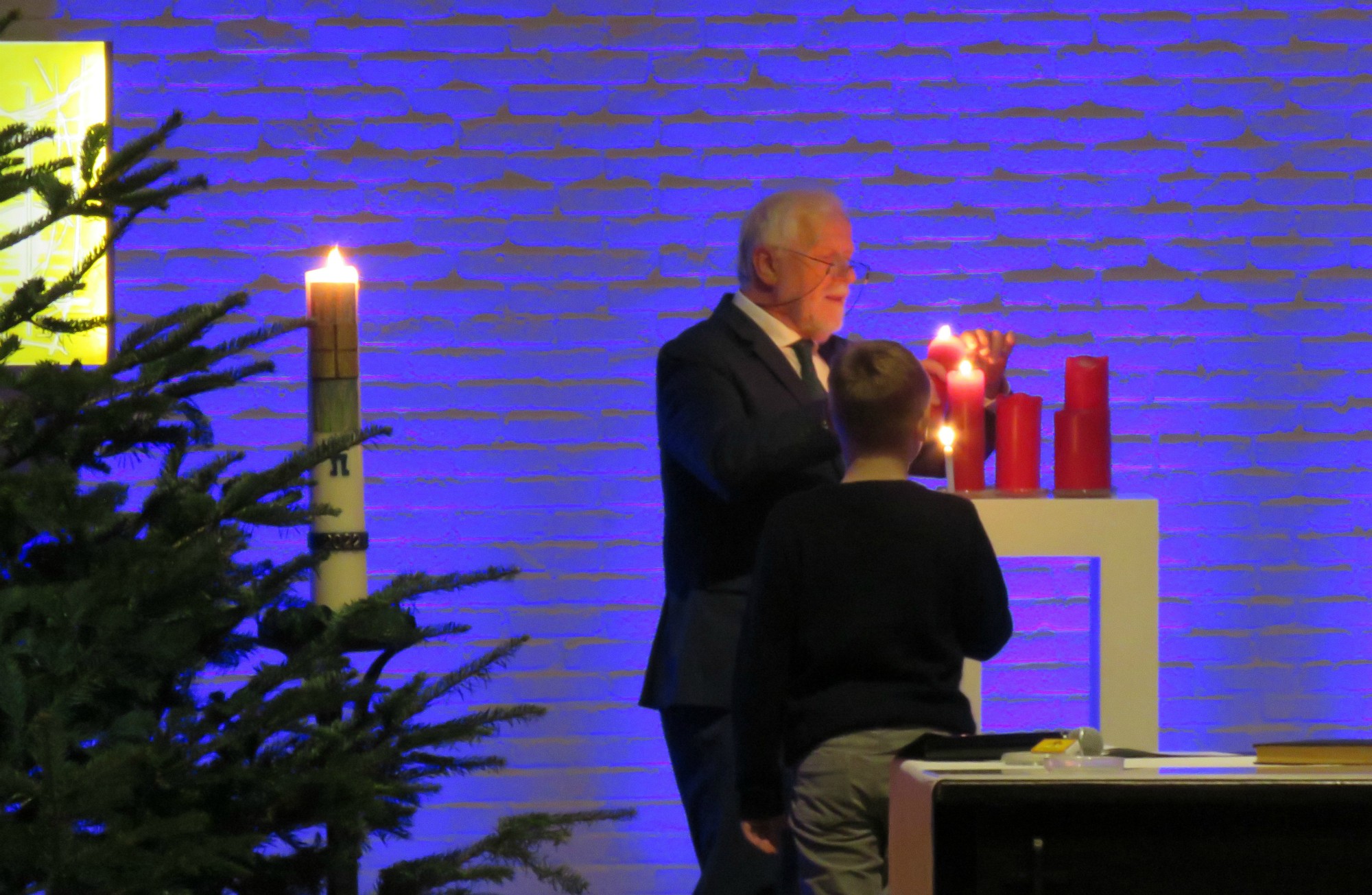Een vormeling ontsteekt alle rode kaarsen achter het altaar bij de Lichtritus